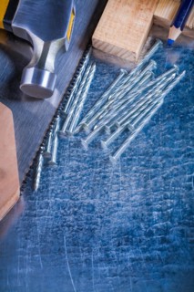 Construction nails claw hammer wooden bricks hand saw pencil on scratched metallic background maintenance concept