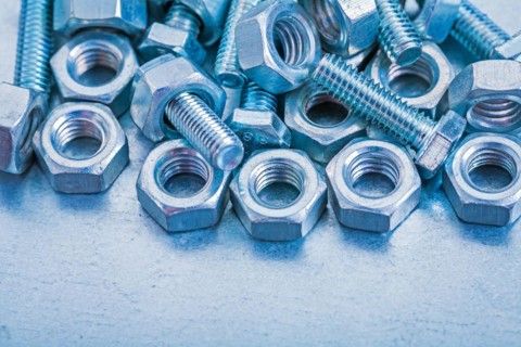Pile of metal bolts and nuts on a metallic background Construction concept