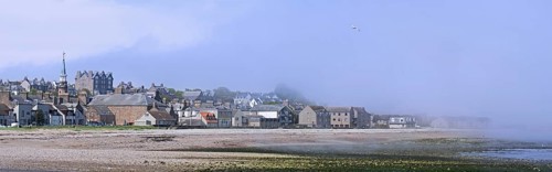 Shingle beach covered in mist and the town Stonehaven