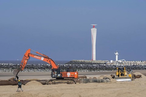 Bulldozer and hydraulic excavator installing pipeline during sand replenishment