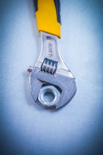 Adjustable spanner and metal screw nut on a metallic background Design concept