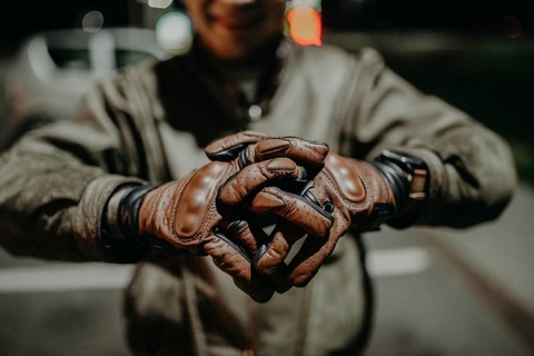 A motorcyclist shows his leather brown gloves for a touring trip to the camera