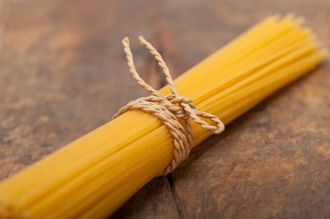 Italian pasta spaghetti tied with a rope on a rustic table