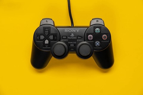Controller of the PS2 Playstation game console from Sony in front of a monochrome yellow background