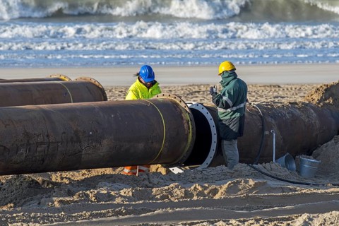 Dredging workers connecting pipes of pipeline during sand replenishment