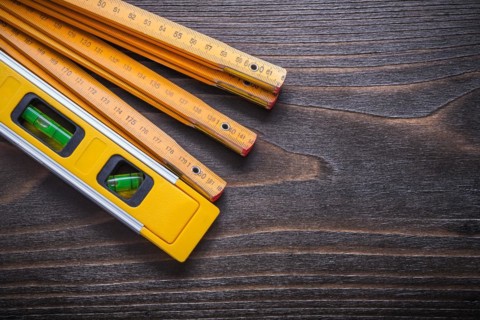 Horizontal view of yellow construction level with wooden metre on vintage wooden board maintenance concept