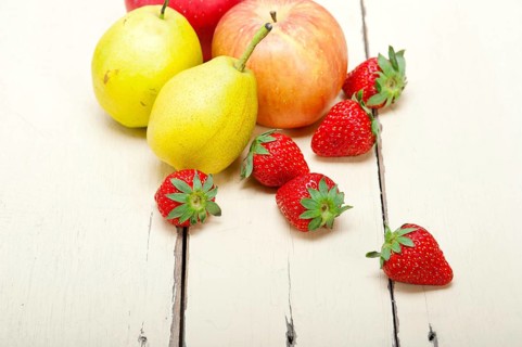 Fresh fruits apples pears and strawberry on a white wood table