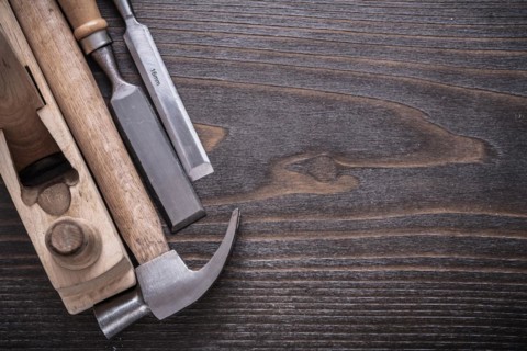 Composition of claw hammer wooden razor plane and flat chisel on vintage wooden board construction concept
