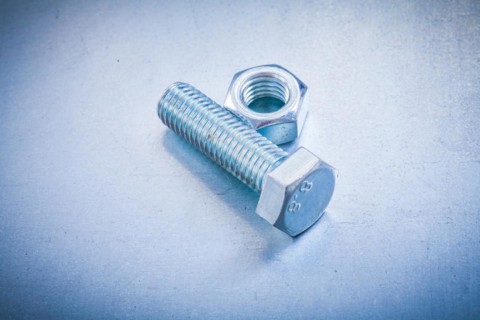Metal construction bolt and nut on metallic background repair concept