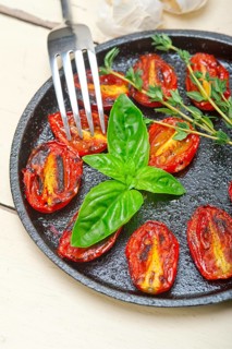 Oven baked cherry tomatoes with basil and thyme on a cast iron skillet