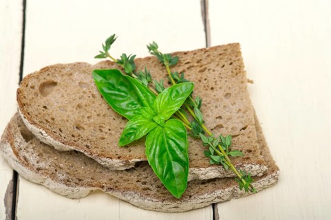 Rustic Italian bread basil and thyme simple snack on white wood table