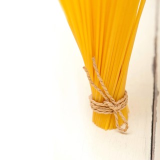 Italian pasta spaghetti tied with a rope on a rustic table