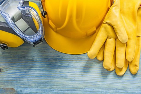 Earmuffs safety glasses gloves hard hat on wooden board construction concept