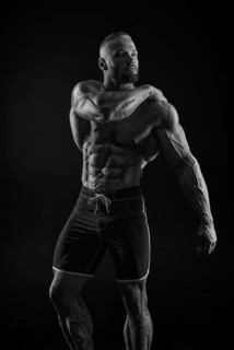 Silhouette of a strong bodybuilder. Confident young fitness athlete with a powerful body and perfect abs. Black and white photography. Dramatic light. Mixed media