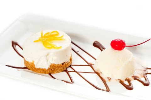 Very elegant lemon mousse dessert served whith lemon peel on top and vanilla ice cream on side