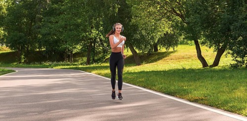 Fitness girl in sportswear runs through the evening sunny park. Healthy lifestyle. Mixed media