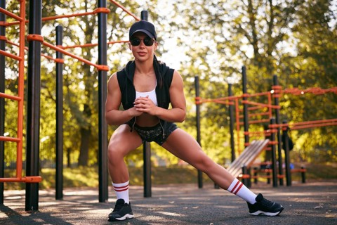 Beautiful young fitness girl is warming up at the stadium before training. Attractive slender brunette in a tracksuit