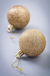 Two gold colored christmas balls on grey background