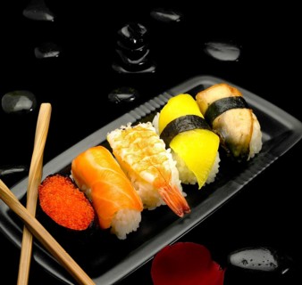 Assorted sushi plate on black pebbles over black background