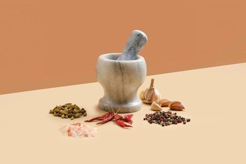 Natural marble mortar and pestle surrounded with spice