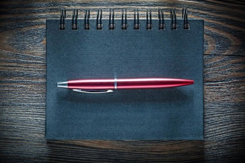 Black notebook pen on vintage wooden board top view