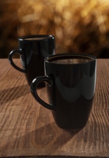 Black cups with coffee on an old wooden board