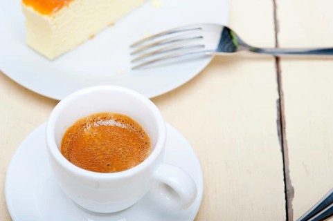 Italian espresso coffee and cheese cake over white wood table