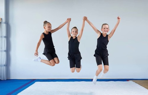 Group of cheerful children are jumping in the gym. Gymnastics concept. Mixed media