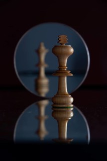 Reflection of a queen chess piece in a mirror