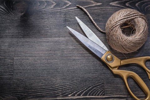 Golden scissors skein of rope on vintage wooden board