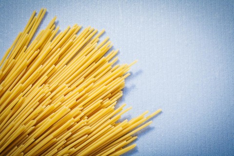 Yellow thin spaghetti on blue background food and drink concept