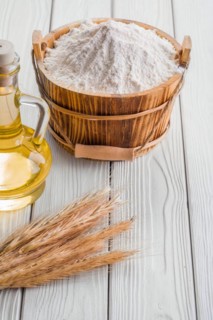 Bucket of flour ears of wheat bottle of oil on old white boards