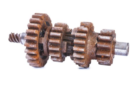 Old dusty and rusty block gearbox against a white background