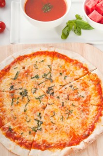 Italian original thin crust pizza Margherita with gazpacho soup and watermelon on side
