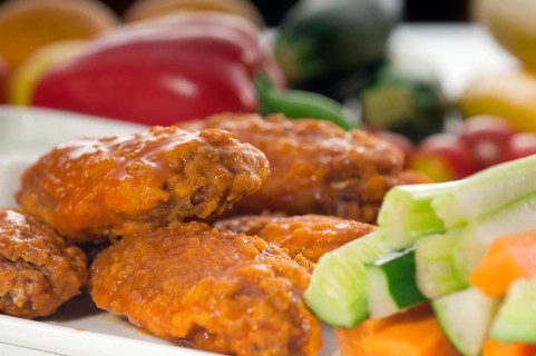 Classic buffalo chicken wings served with fresh pinzimonio and vegetables on background
