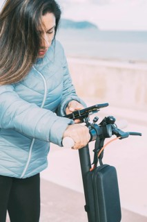 Side view of Beautiful latin woman riding her motorized scooter in the city
