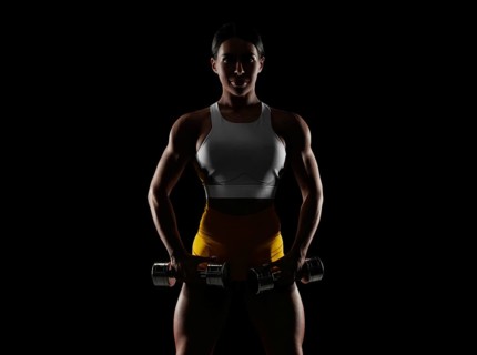 Brutal sports woman pumps up muscles with dumbbells. Fitness concept. Mixed media