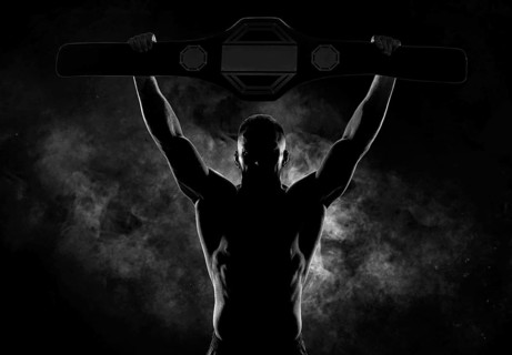 Kickboxer victoriously raises the belt won in the tournament against the backdrop of smoke. Sports competitions. Fight night. The concept of mixed martial arts. MMA