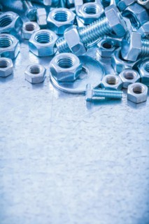 Pile of stainless steel threaded screws nuts and bolts washers on metallic background Construction concept