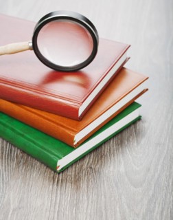 Notebooks and magnifying glass on a wooden background