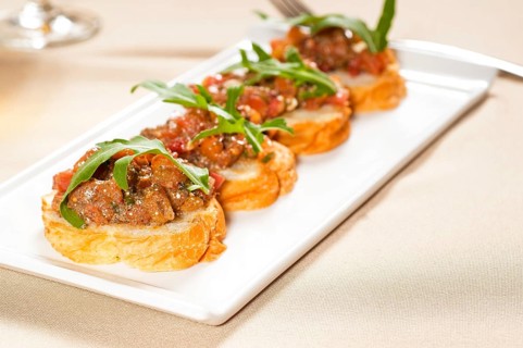Fresh tipycal italian bruschetta with tomato and arugula on top