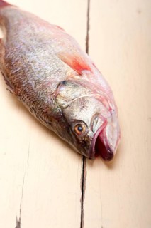 Fresh whole raw fish on a wooden table ready to cook