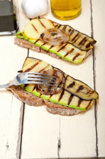 Grilled vegetables on rustic bread over wood table