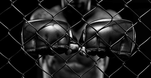 Black and white image of a man in a boxing cage. The concept of sports
