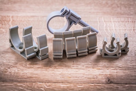 Set of plastic pipe fasteners on wooden board