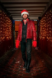 Man dressed as Santa Claus poses on a street decorated with garlands. New Year and Christmas concept. Mixed media