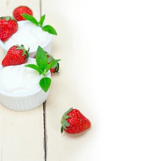 Organic Greek yogurt and strawberry over white rustic wood table