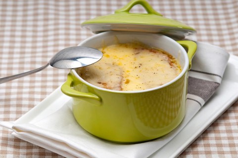 Onion soup on clay pot with melted cheese and bread on top