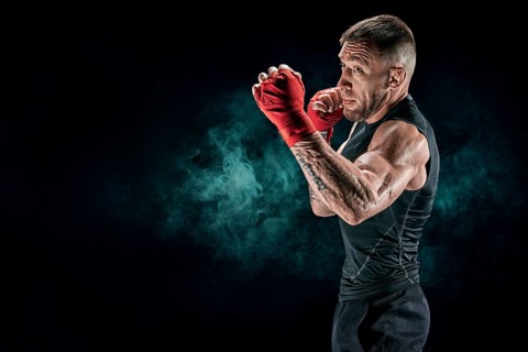 Kickboxer in red bandages is boxing against a background of smoke. The concept of mixed martial arts. MMA
