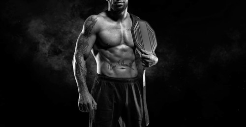 Kickboxer with a belt on his shoulder poses against a background of smoke. Sports competitions. Fight night. The concept of mixed martial arts. MMA